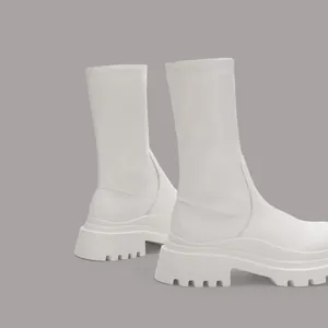 Detailed side view of white platform elastic mid-calf boots with chunky lug sole.