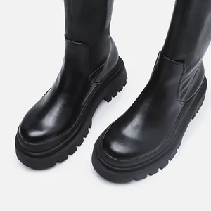 Close-up detail of black chunky lug-sole mid-tube boots with smooth synthetic leather finish