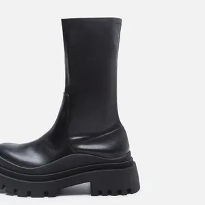 Close-up side view of professional black stretch mid-calf boots with chunky platform soles.
