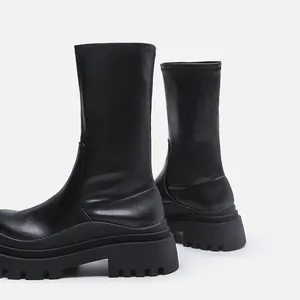 Detailed side view of black lug-sole platform elastic mid-calf boots