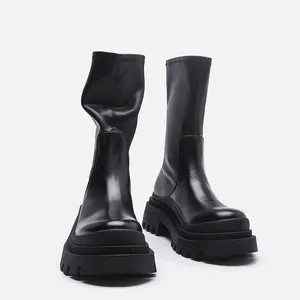 Detailed view of black chunky platform mid-calf stretch boots with thick lug soles