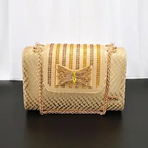 Elegant gold snakeskin evening clutch bag featuring a rhinestone bow and chain strap