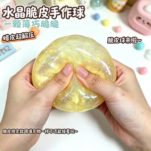Close-up of a yellow glittery crystal slime stress ball being squeezed by person's hands.