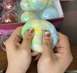 Gros plan de mains pressant une balle anti-stress colorée faite à la main.