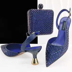 Elegantes zapatos de tacón azul con pedrería y bolso de mano de noche a juego set