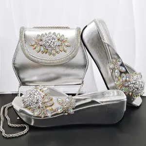 Elegantes Set aus silbernen Plateausandalen und Handtasche mit verzierten Strassblumen.