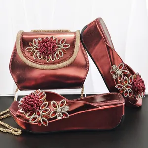 Detailaufnahme von weinroter Handtasche und Keilsandaletten mit verzierten Kristallen