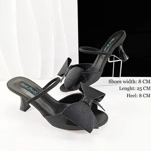 Detailaufnahme schwarzer Satin-Pumps mit offener Zehenpartie, Schleife und 8 cm Absatz