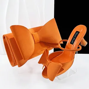 Elegantes Set aus orangefarbenen Satin-Heels und passender Clutch mit Schleife