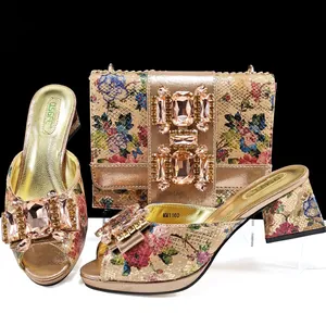 Detailansicht der geblümten Schlangenprint-Sandalen und passender Clutch mit Strassschnallen.