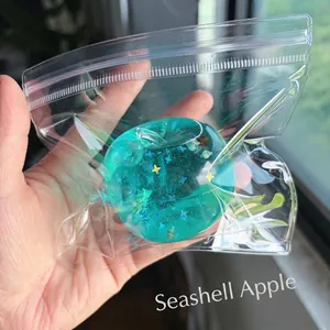 Detailansicht eines durchsichtigen Apfel-Squishies mit Muscheln und Sternenglitzer.