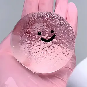 Gros plan d'une balle anti-stress rose transparente avec un joli design de smiley.