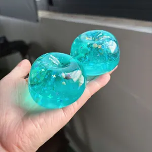 Nahaufnahme eines blauen, durchsichtigen Apfel-Squishys mit Muscheln und Sternen