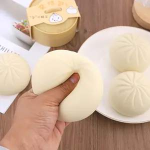 Dettaglio di una mano che schiaccia un realistico giocattolo squishy a forma di panino Baozi.