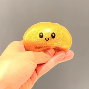 Primo piano di una mano che spreme un giocattolo antistress a forma di panino dorato