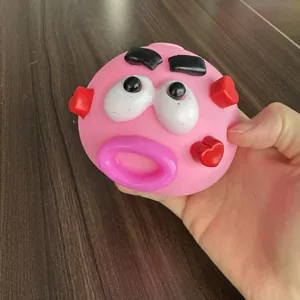 Funny pink face expression stress relief squeeze ball toy with hearts held in hand.