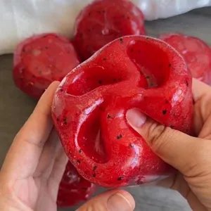 Nahaufnahme eines roten Wassermelonen-Squishy-Spielzeugs beim Zusammendrücken