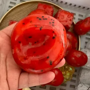 Κοντινό πλάνο ενός γυαλιστερού κόκκινου squishy καρπουζιού με ρεαλιστική μαλακή υφή.