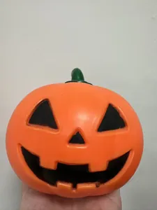 Detailansicht eines orangefarbenen Halloween Kürbis Stressspielzeugs, in der Hand gehalten