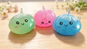 Κοντινό πλάνο από τρία glitter unicorn dumpling squishies σε ένα ξύλινο τραπέζι.
