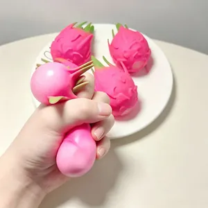 Gros plan d'une main pressant un jouet anti-stress fruit du dragon rose sur une assiette