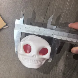 Jouet à presser crâne blanc mesuré avec un pied à coulisse pour démonstration de taille