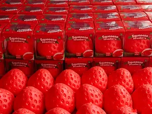 Realistic giant strawberry squeeze toys displayed in red retail packaging for stress relief