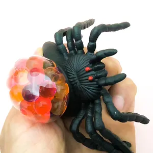 Detailansicht einer Hand, die ein schwarzes Spinne-Stressspielzeug mit bunten Perlen drückt