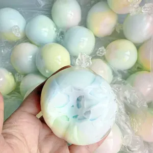 Detailed close-up of a pastel gradient stress relief squishy ball toy held in hand.