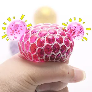 Pink mesh squeeze grape ball stress toy with glitter being squeezed by hand