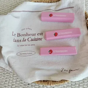 Close-up detail showing three pink strawberry squishies on a white decorative cloth