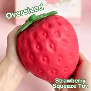 Close-up view of an extra large red strawberry slow rebound squishy stress relief toy being held
