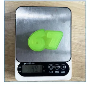 Close-up of green number 67 TPR squishy toy being weighed on a digital scale