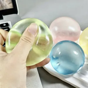 Close-up of a hand squeezing a colorful, translucent stress relief squishy ball.
