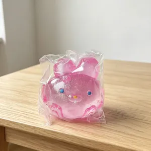 Close-up detail of a cute pink glitter rabbit squishy toy in plastic packaging.
