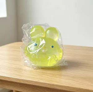 Translucent lime green rabbit squishy toy in packaging on wooden surface