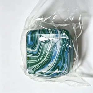 Close-up view of a blue marble pattern square squishy toy in its clear plastic packaging bag