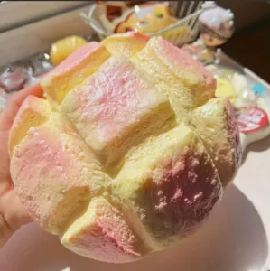 Nahaufnahme eines rosa und gelben Brot-Squishy-Spielzeugs mit weicher Textur und Form.