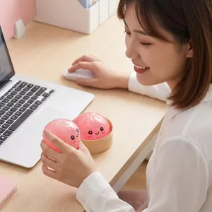Dettaglio di un gioco antistress a forma di baozi rosa premuto su una scrivania