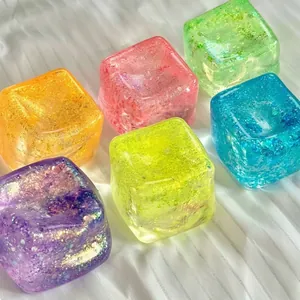 Close-up of colorful glitter maltose ice cube squeeze toys on white fabric