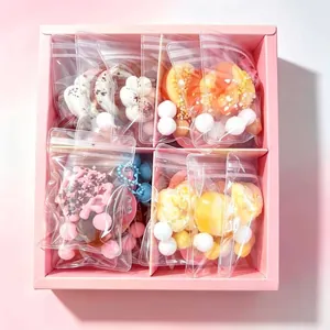 Vista detallada de varios colgantes squishy de comida en una caja de regalo rosa