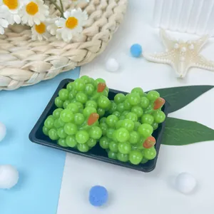 Vue détaillée de jolis jouets spongieux en forme de raisins verts dans un plateau