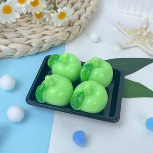 Vue détaillée de quatre jouets à presser pomme verte sur un plateau noir avec décor