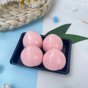 Gros plan sur quatre jouets spongieux en forme de pêche rose dans un plateau noir