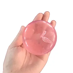 A soft pink translucent apple-shaped squishy stress relief toy held in a person's hand