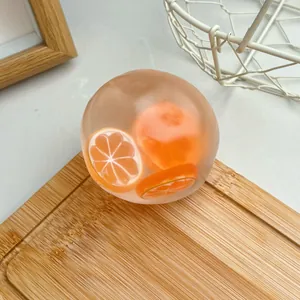 Vue détaillée d'une balle anti-stress aux fruits transparente avec tranches d'orange