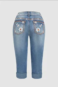 Vista trasera de pantalones vaqueros capri para mujer con bordados de margaritas.
