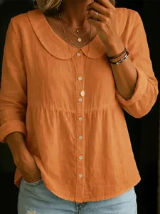 Detailaufnahme einer Frau in einer lässigen orangefarbenen Bluse mit Bubikragen.