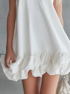 Primer plano de minivestido blanco con volantes que muestra la textura y el dobladillo.