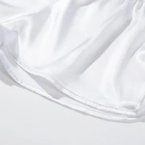 Makro-Detail zeigt die glatte Textur und die Nähte des weißen Satin-Herrenshorts-Stoffs.